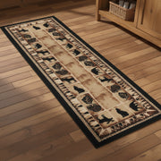 A long rectangular area rug with a rustic western-style design, featuring black silhouettes of deer, bears, and moose on a tan and brown background with a black border.