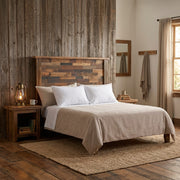 Castle Peak Barnwood Patchwork Headboard in a rustic farmhouse bedroom with a weathered barnwood wall, lantern lamp nightstand, and jute rug