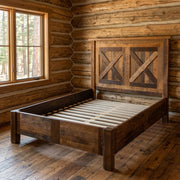 Cleveland Peak Barnwood Barn Door Bed with Rail System staged in a sunlit log cabin bedroom