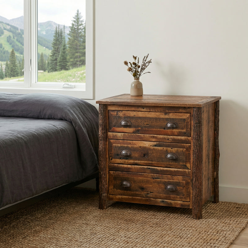 Clinton Peak Barnwood Nightstand beside a bed with gray bedding and a small vase near a bright window