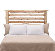 Front view of the Grizzly Peak Cedar Live Edge Headboard in natural cedar finish with white pillows and tan bedding