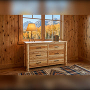 Hagerman Peak Cedar Log Dresser with a lamp and books below a window framing golden aspens and mountains in a knotty pine lodge room