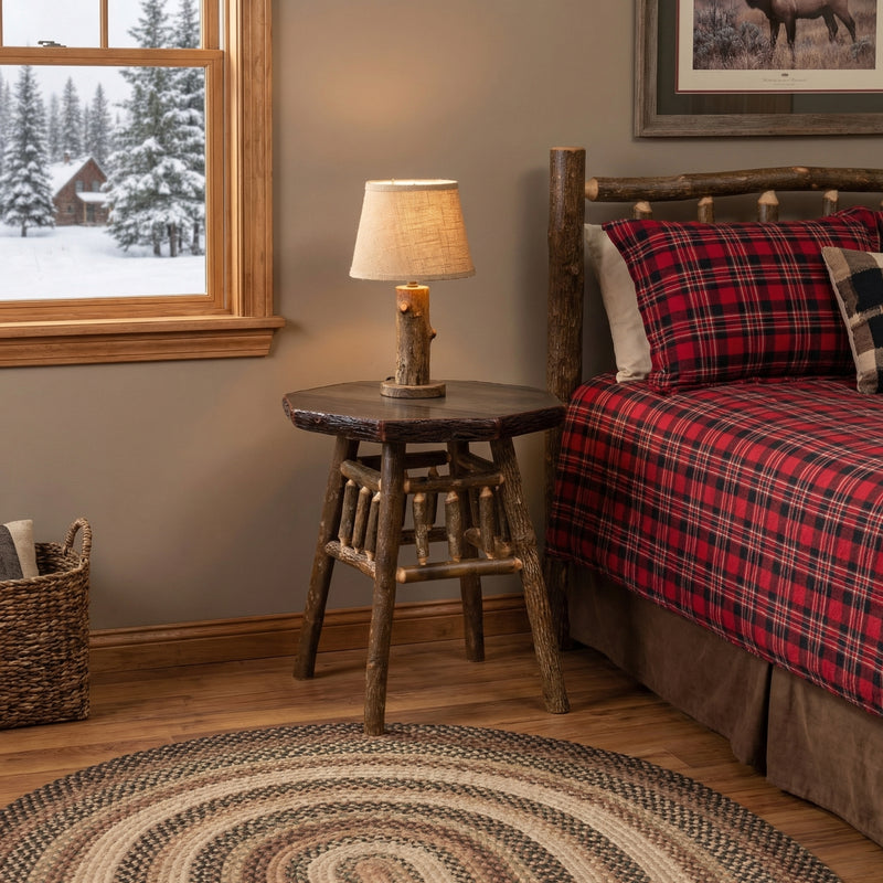 Hagues Peak Hickory Log Spindle Nightstand in Slate with a table lamp beside a plaid-covered bed near a snowy window