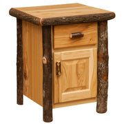 Angled view of the Hallett Peak Hickory Log Enclosed Nightstand in Natural showing the drawer, cabinet door, and bark-on posts