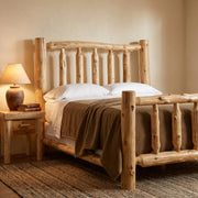 Angled view of the Longs Peak Cedar Log Bed handcrafted from solid cedar logs in a rustic cabin bedroom