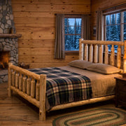 Longs Peak Cedar Log Bed staged in a rustic log cabin bedroom with stone fireplace and plaid bedding