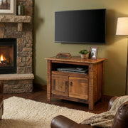Lulu Mountain Reclaimed Barnwood TV Stand holding a TV beside a window in a cozy room