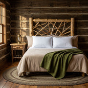 Mount Democrat Cedar Log Twig Headboard in a dark log-walled woodland cabin with a moss green blanket and braided rug