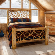 Mount Elbert Cedar Log Twig Bed in a sunlit cabin loft bedroom with snowy forest windows and a cedar log dresser