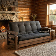 Mount Epaulet Pine Futon staged in a rustic log cabin living room with a stone fireplace