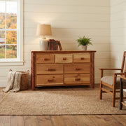 Mount Garfield Hickory Log Dresser in Natural with a lamp and plant on top in a bright bedroom beside a wood chair
