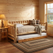 Mount Guyot Cedar Log Daybed with roll-out trundle in a pine-paneled cabin room with a braided rug and plaid pillows