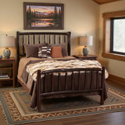 Mount Lincoln Hickory Log Bed with patterned bedding beneath a mountain landscape painting in a warm lodge bedroom with a southwestern rug