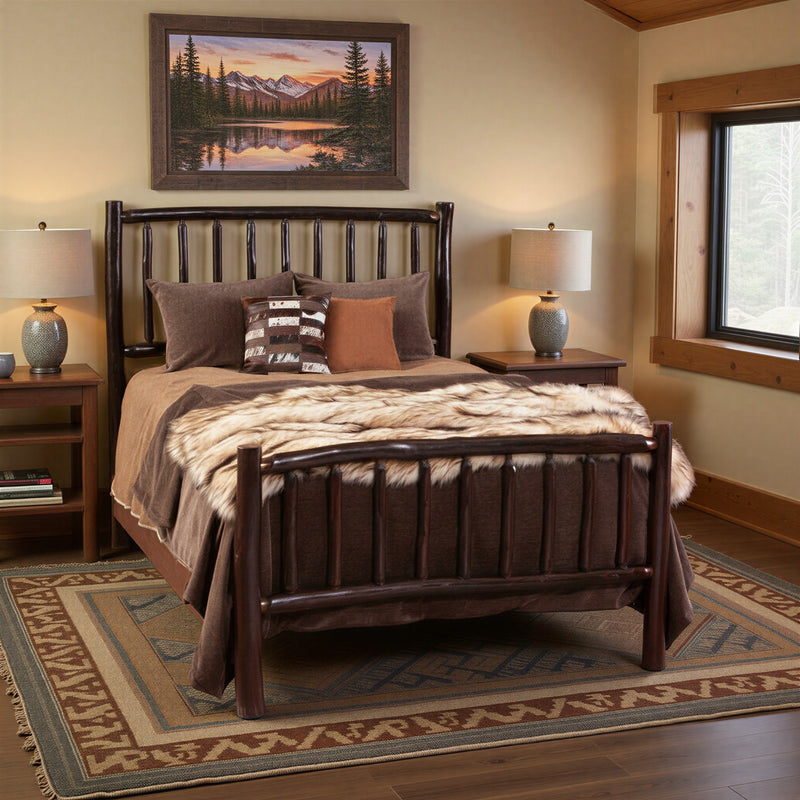 Mount Lincoln Hickory Log Bed with patterned bedding beneath a mountain landscape painting in a warm lodge bedroom with a southwestern rug