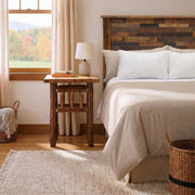 Mount Sopris Hickory Log Nightstand in Natural beside a bed with white bedding and a table lamp near a bright window