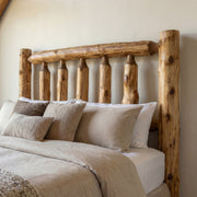Quandary Peak Cedar Log Headboard behind layered taupe and white pillows in a softly lit cabin bedroom