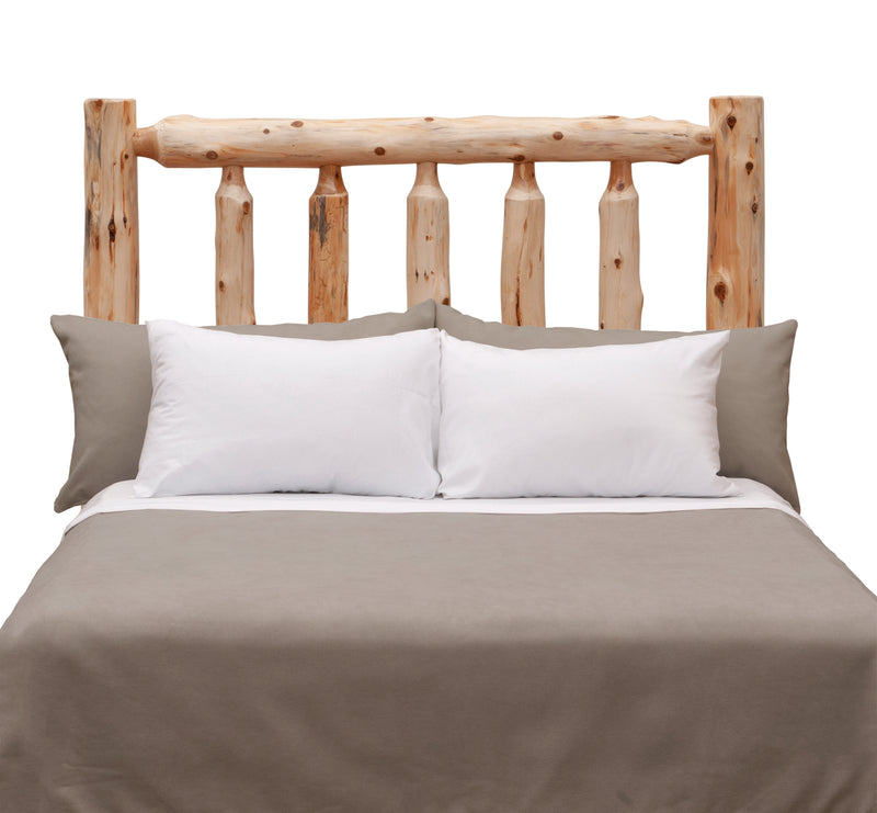 Front view of the Quandary Peak Cedar Log Headboard styled with white pillows and gray bedding