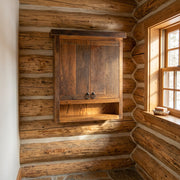 Santa Fe Peak Reclaimed Barnwood Over the Toilet Cabinet staged in a sunlit log cabin bathroom