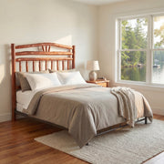 Sunlight Peak Hickory Wagon Wheel Headboard with gray bedding in a bright bedroom with a lake and forest window view
