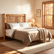 Torreys Peak Cedar Log Spindle Headboard with tan bedding in a sunny bedroom with autumn window view and table lamp