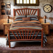 Uncompahgre Peak Hickory Sunburst Bed with a southwestern striped blanket between pine nightstands in a rustic bedroom with a brick wall and clock