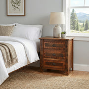Wilson Peak Reclaimed Barnwood Three Drawer Bedside Chest with a table lamp beside a bed with white bedding near a mountain-view window