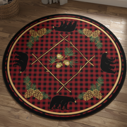 A circular decorative rug or mat featuring a red and black buffalo plaid background with black bear silhouettes, pine trees, pinecones, acorns, and crossed wooden poles arranged symmetrically.